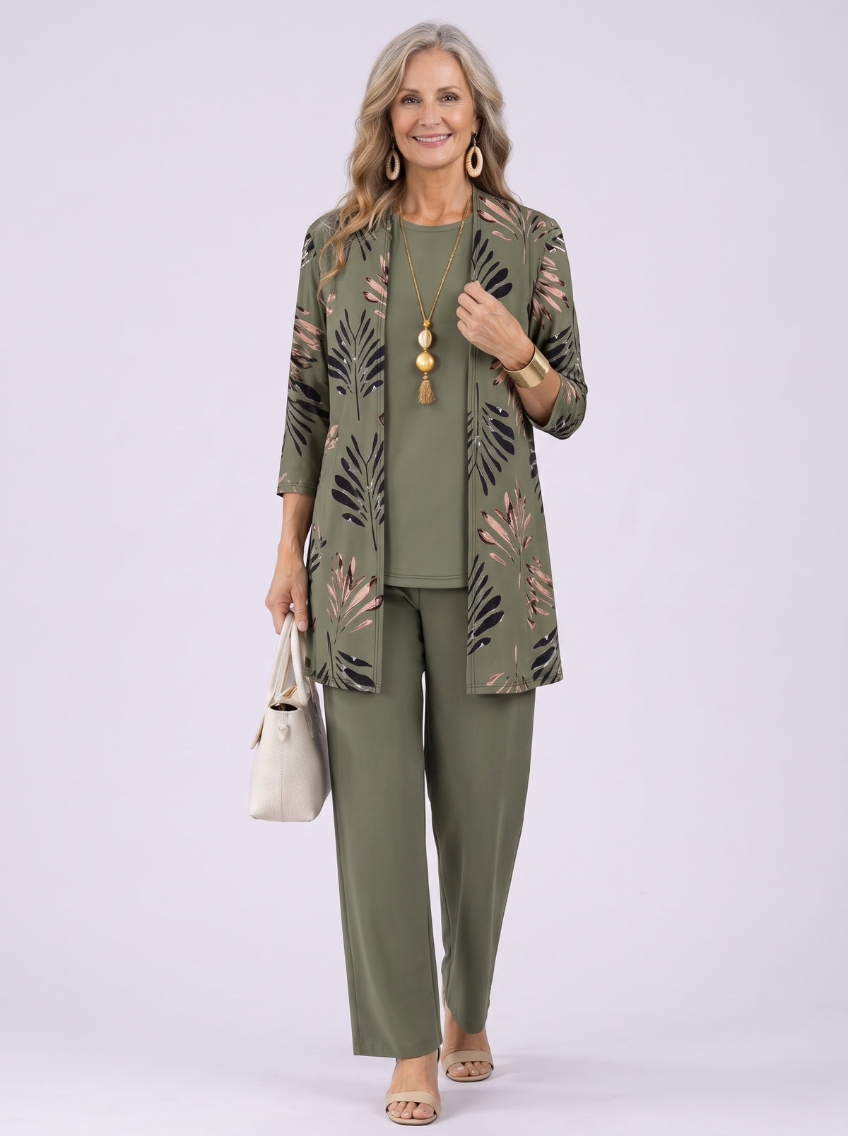 Donna con completo SIRMIONE verde oliva: cardigan lungo aperto con foglie nere e rosa, top girocollo e pantalone ampio