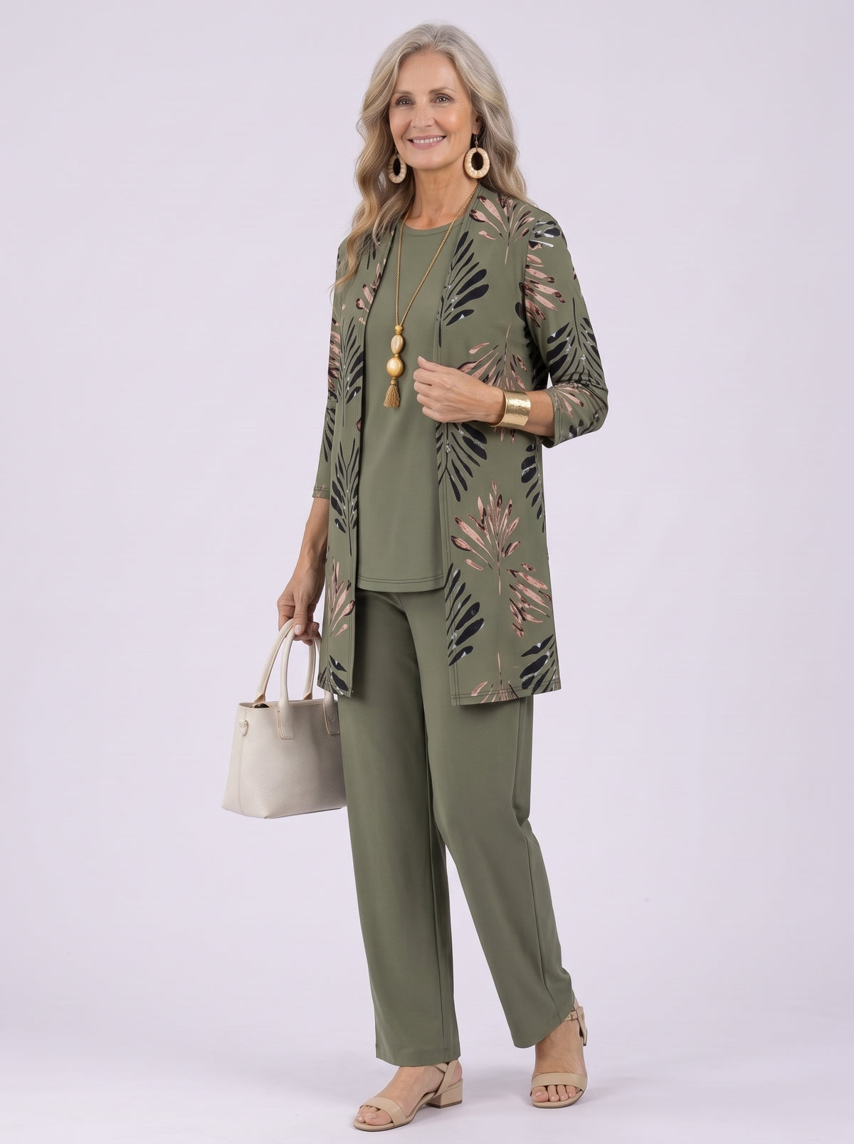 Donna con completo verde oliva: cardigan lungo con stampa di foglie nere e rosa, top girocollo in tinta unita e pantalone ampio